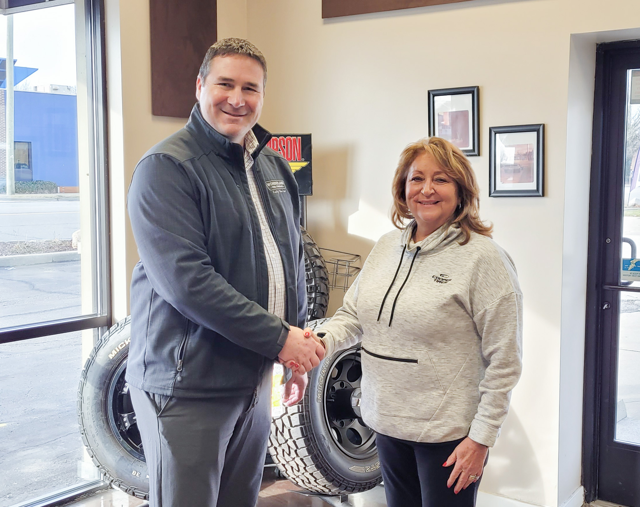 Dave Langerak (Chief Operating Officer of Wonderland Tire) and Patti Piscione (Former Owner of Carter Tire & Automotive) shake hands