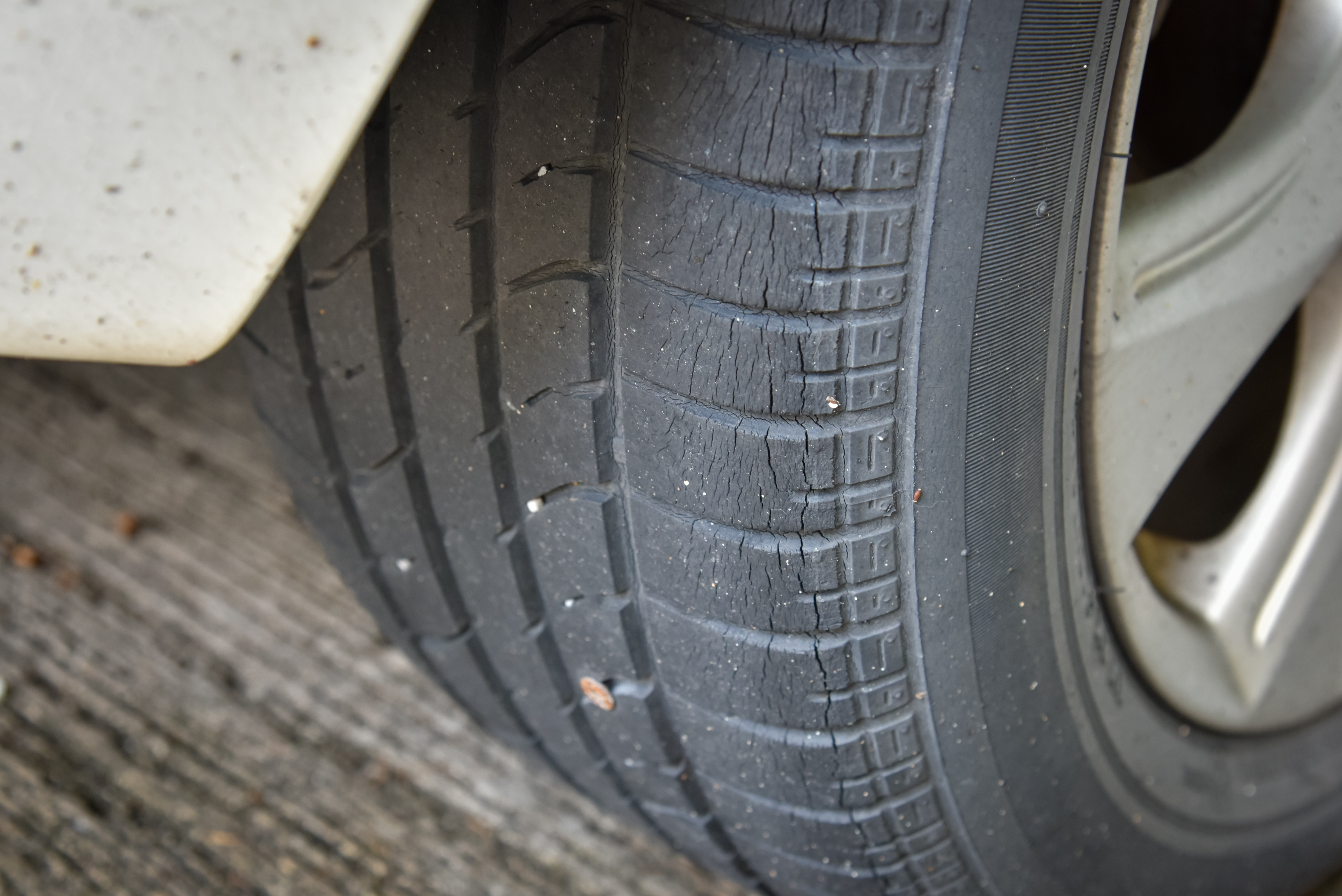 A car tire with sidewall and tread cracking.
